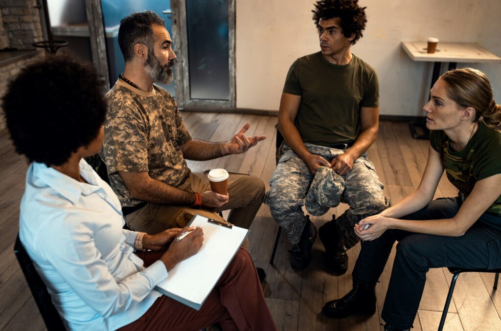 Group of diverse veterans talking during PTSD support group.