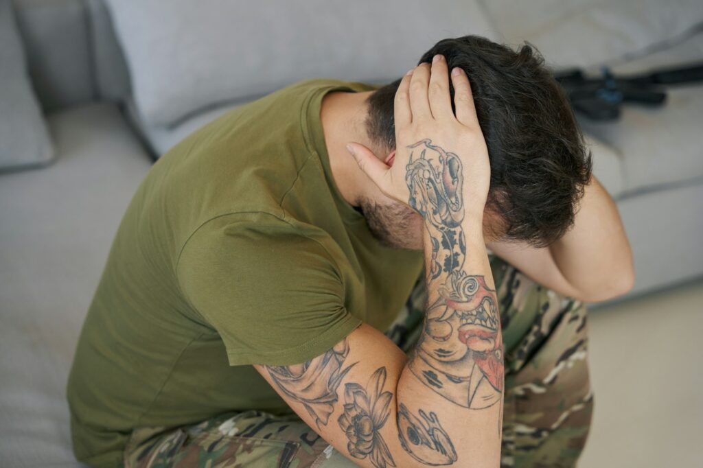 Serviceman grabbing head with hands while suffering from PTSD